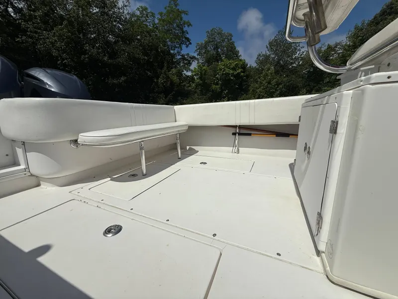 Slide: The Image of 2002 Contender 27 Tournament boat interior with seating and storage, surrounded by lush greenery. - 25