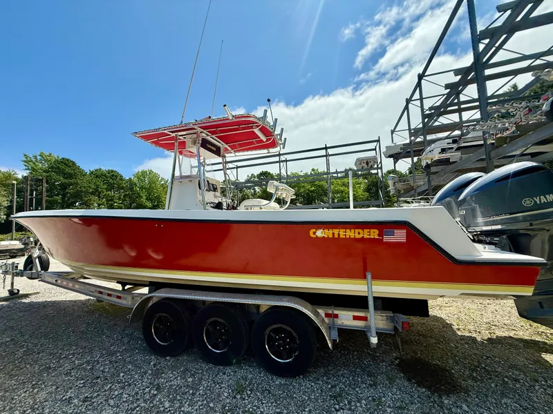 Slide: The Image of 2002 Contender 27 Tournament boat on trailer, red hull, parked outdoors under blue sky. - 37