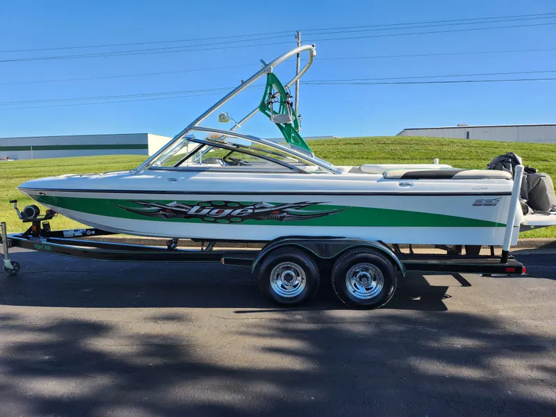 Slide: The Image of 2007 Tigé 22i boat with green accents on a trailer, parked outdoors. - 5