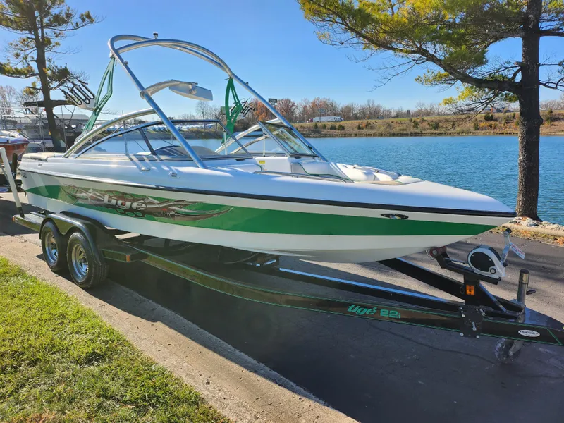 Slide: The Image of 2007 Tigé 22i boat with green accents on a trailer by a lake. - 8