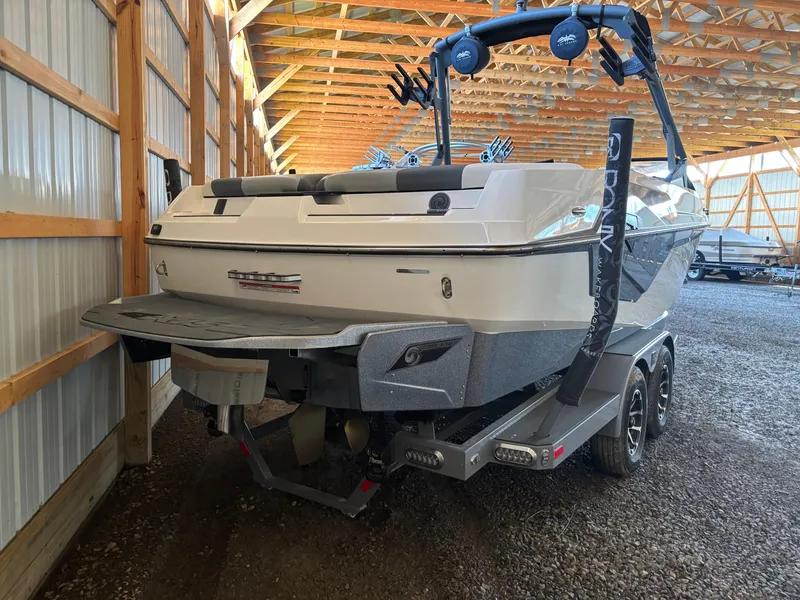 Slide: The Image of 2020 Axis T23 boat in storage, rear view, showcasing trailer and wakeboard tower. - 1