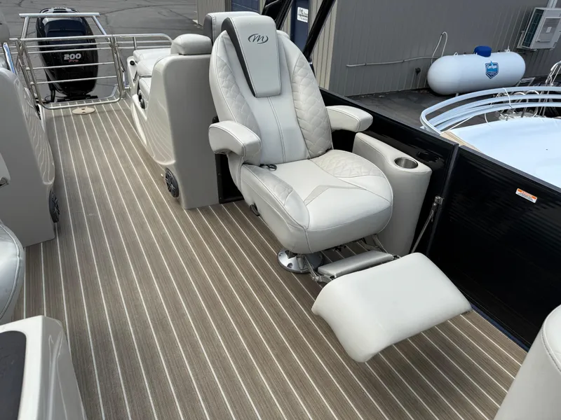 Slide: The Image of 2017 Manitou 24 Legacy Triple Tube boat interior with luxurious seating and striped flooring. - 15