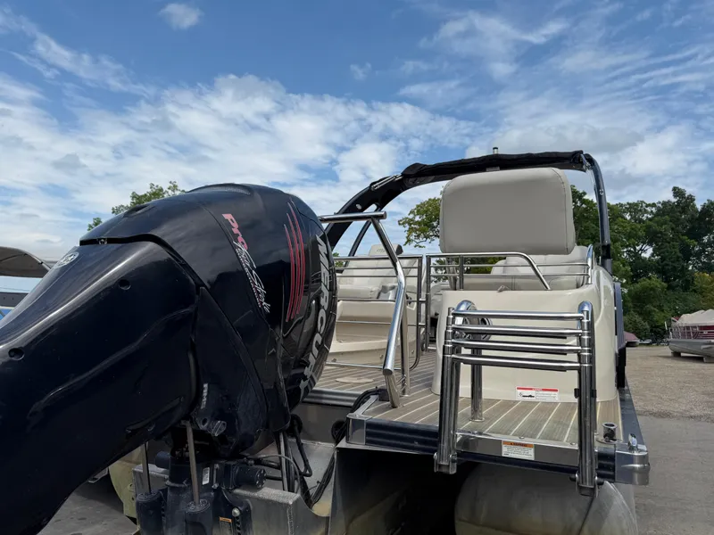 Slide: The Image of 2017 Manitou 24 Legacy Triple Tube pontoon boat with Mercury outboard motor, docked under blue sky. - 2