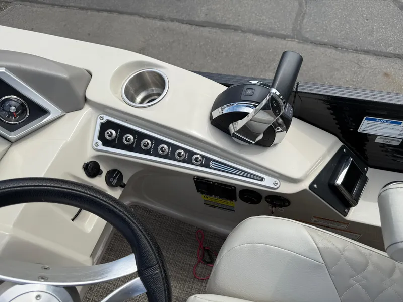 Slide: The Image of 2017 Manitou 24 Legacy Triple Tube boat dashboard with controls and steering wheel. - 21