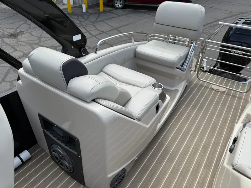 Slide: The Image of 2017 Manitou 24 Legacy Triple Tube boat interior with beige seating and striped flooring. - 25