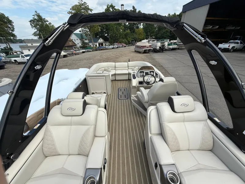 Slide: The Image of 2017 Manitou 24 Legacy Triple Tube pontoon boat interior with luxurious seating and steering console. - 29