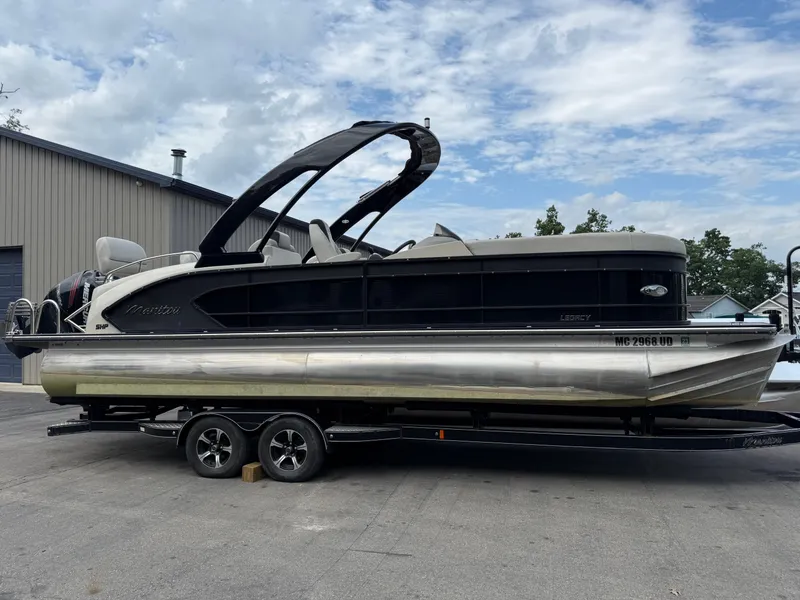 Slide: The Image of 2017 Manitou 24 Legacy Triple Tube pontoon boat on trailer, parked outdoors. - 3