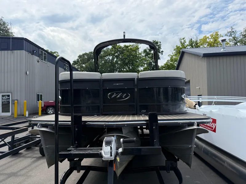 Slide: The Image of 2017 Manitou 24 Legacy Triple Tube pontoon boat on trailer, parked outside a building. - 5