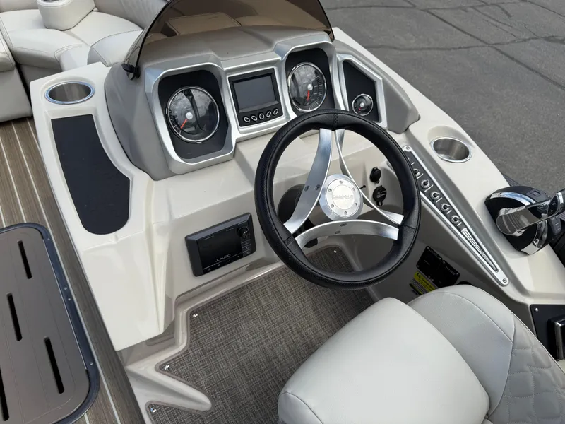 Slide: The Image of 2017 Manitou 24 Legacy Triple Tube boat dashboard with steering wheel and controls. - 8