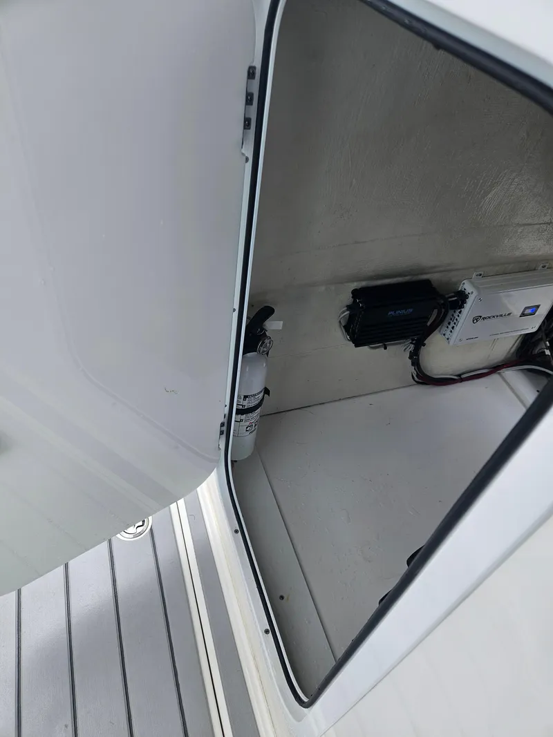 Slide: The Image of Open storage compartment in 2022 Sea Cat 260 Hybrid boat, showing interior equipment and fire extinguisher. - 19
