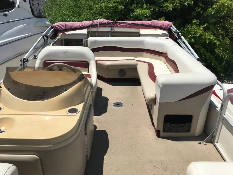Slide: The Image of 2000 Fisher Freedom 241 DLX pontoon boat with beige and maroon seating, docked outdoors. - 9