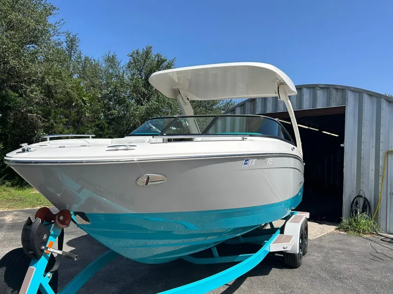 Slide: The Image of 2022 Regal LS4 Surf boat on trailer, parked outside metal building. - 10