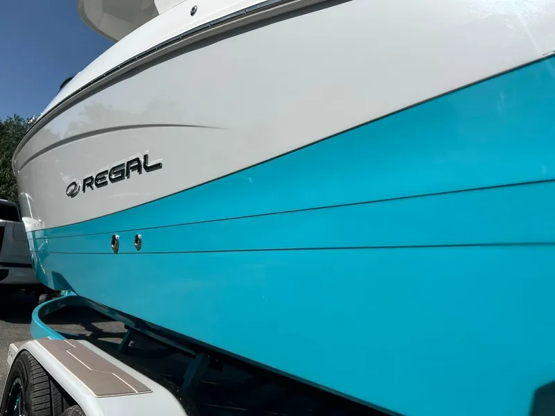 Slide: The Image of 2022 Regal LS4 Surf boat with blue and white exterior on a trailer. - 17