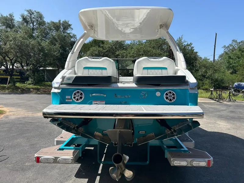 Slide: The Image of 2022 Regal LS4 Surf boat, rear view, teal color, parked outdoors. - 23