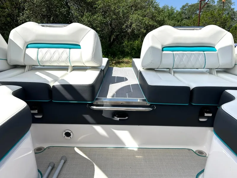 Slide: The Image of 2022 Regal LS4 Surf boat interior with white and teal seating, outdoor setting. - 43