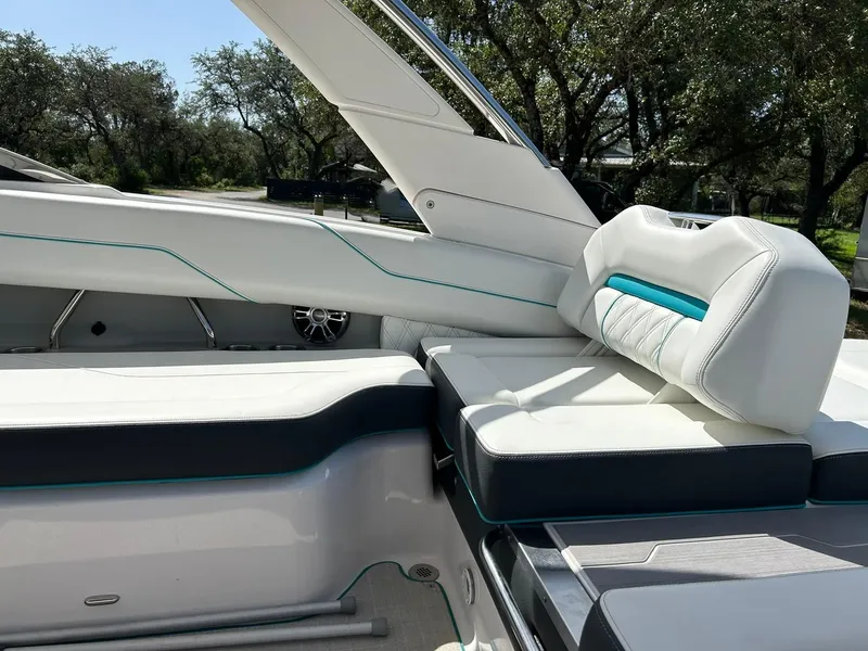 Slide: The Image of 2022 Regal LS4 Surf boat interior with white and teal seating, outdoor setting. - 44