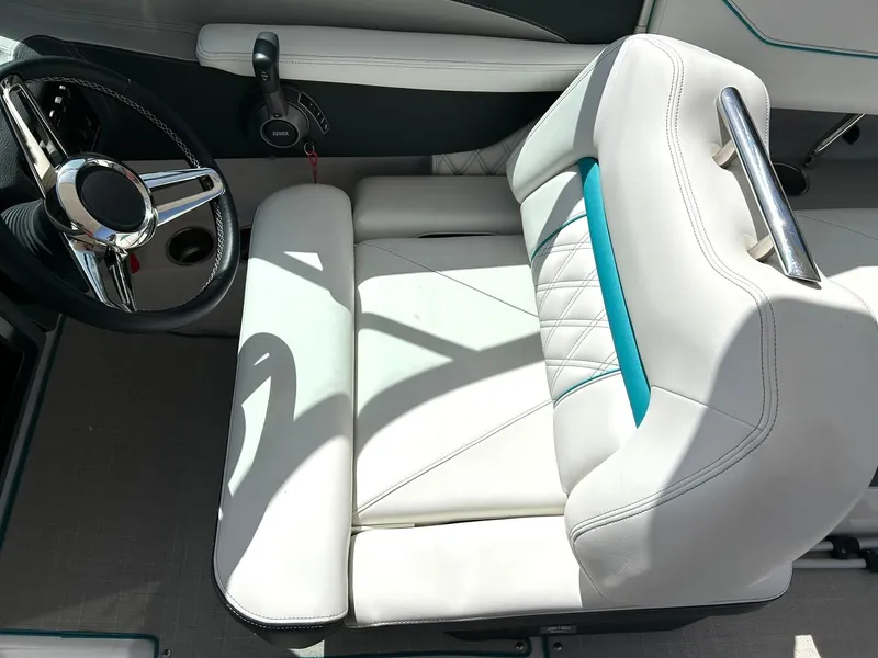 Slide: The Image of 2022 Regal LS4 Surf boat interior with white and teal seating and steering wheel. - 49