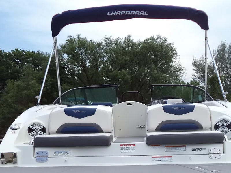 Slide: The Image of 2017 Chaparral Vortex 223 VR boat with canopy, rear seating, and lush greenery background. - 6