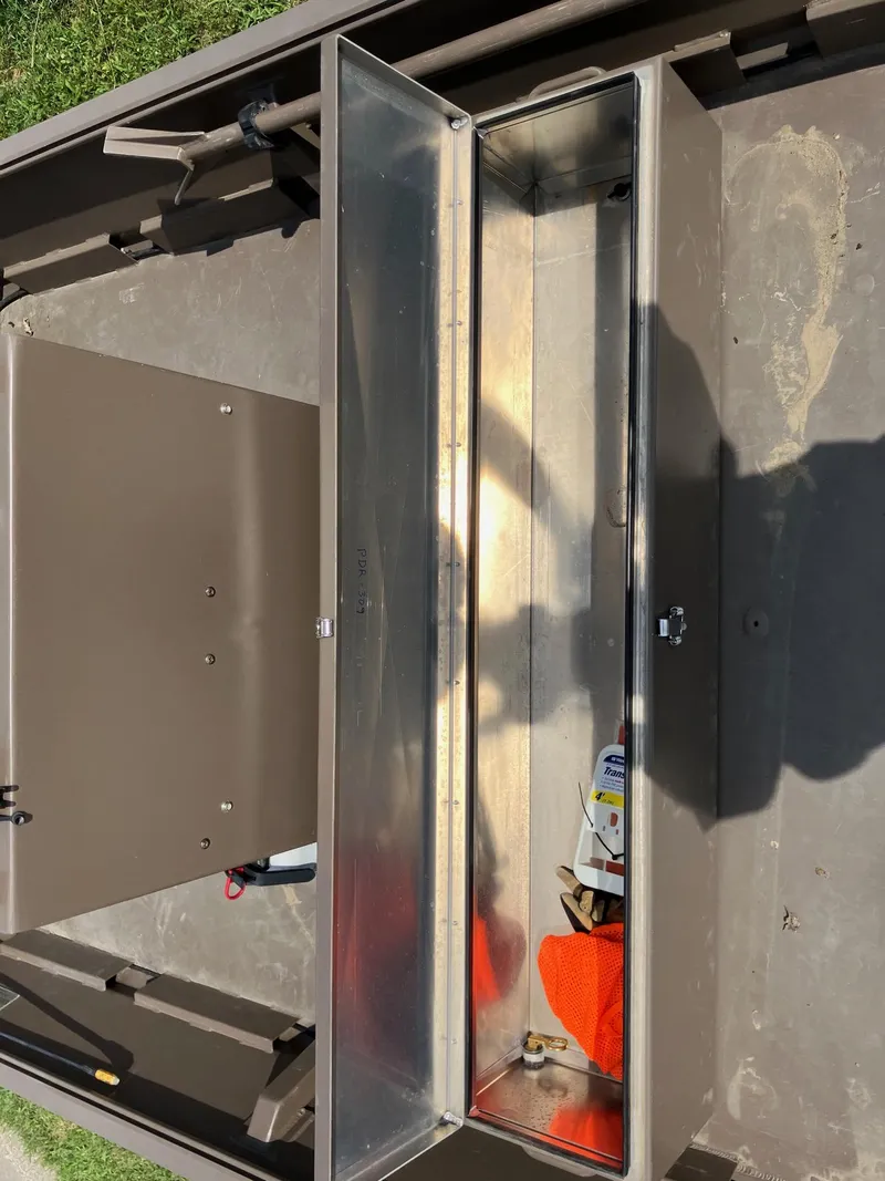 Slide: The Image of Open storage compartment in a 2017 Pro-Drive SBX Series 18' boat, showing interior contents. - 13