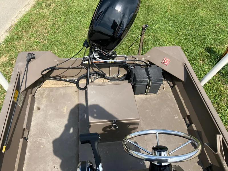 Slide: The Image of 2017 Pro-Drive SBX Series 18' boat interior with steering wheel and motor, on grass. - 16