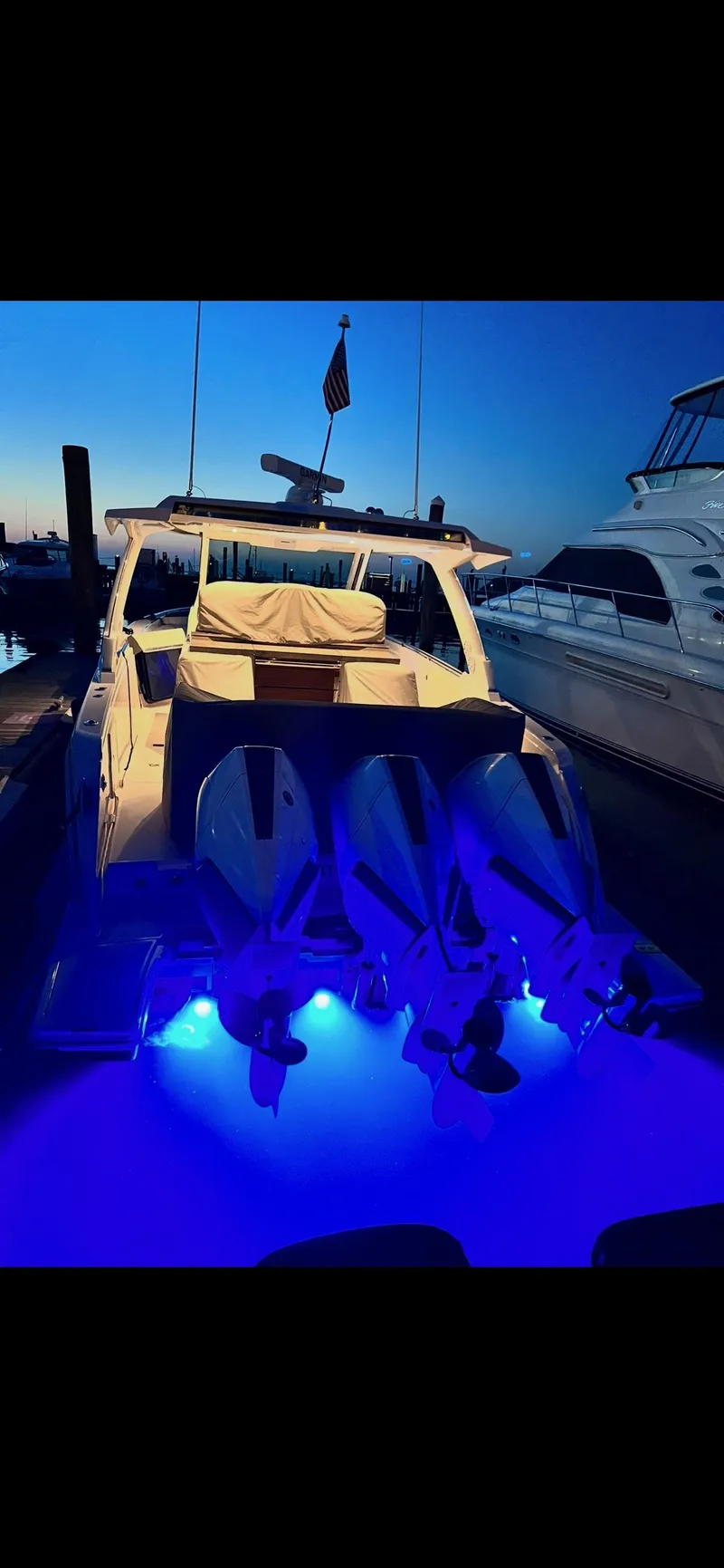 Slide: The Image of 2023 Tiara Yachts 38 LS with illuminated blue underwater lights at dusk. - 2