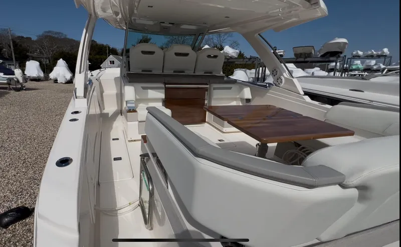 Slide: The Image of 2023 Tiara Yachts 38 LS interior with seating and wooden table, docked outdoors. - 4