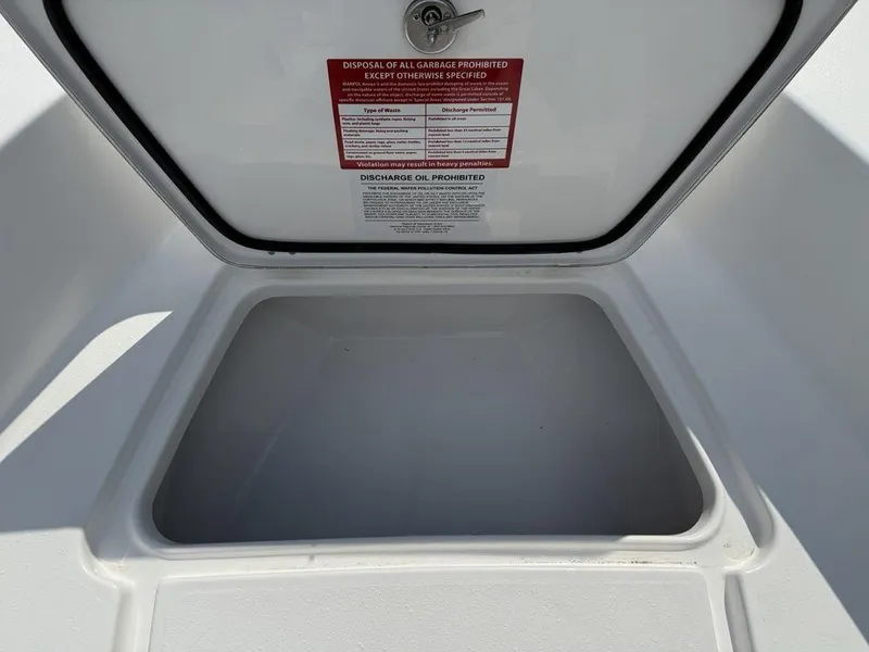 Slide: The Image of Open storage compartment on 2026 Tidewater 180 CC Adventure boat with waste disposal warning. - 11