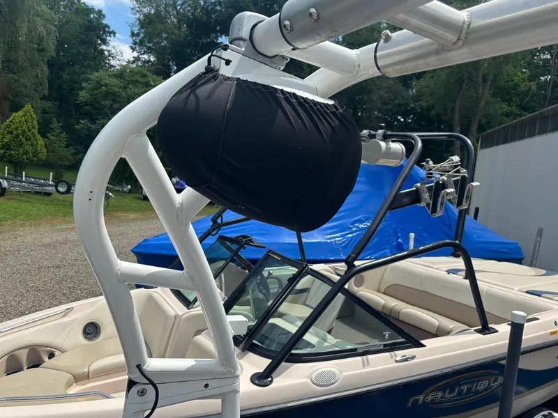 Slide: The Image of 1989 Correct Craft Ski Nautique boat with wakeboard tower and cover, parked outdoors. - 15