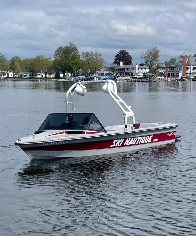 Slide: The Image of 1989 Correct Craft Ski Nautique boat on a calm lake with houses in the background. - 7