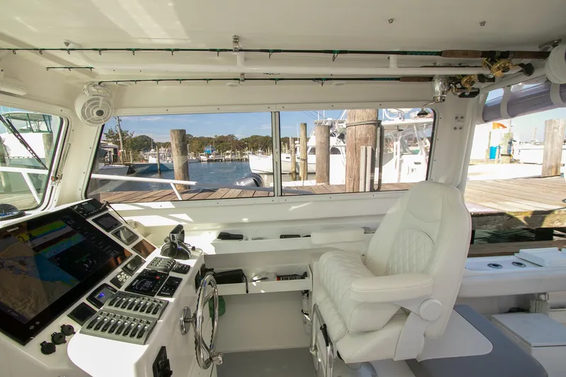 Slide: The Image of 2026 Steiger Craft 31 Miami boat interior with helm, white captain's chair, and marina view. - 35