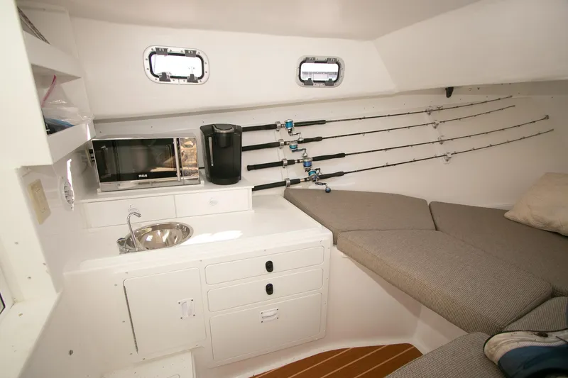 Slide: The Image of 2026 Steiger Craft 31 Miami cabin with kitchenette, fishing rods, and seating area. - 43