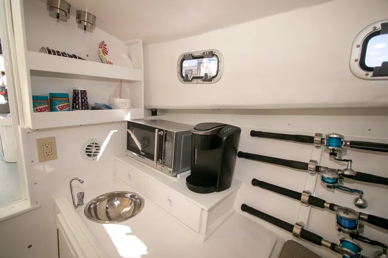 Slide: The Image of 2026 Steiger Craft 31 Miami cabin with kitchenette, fishing rods, and appliances. - 44