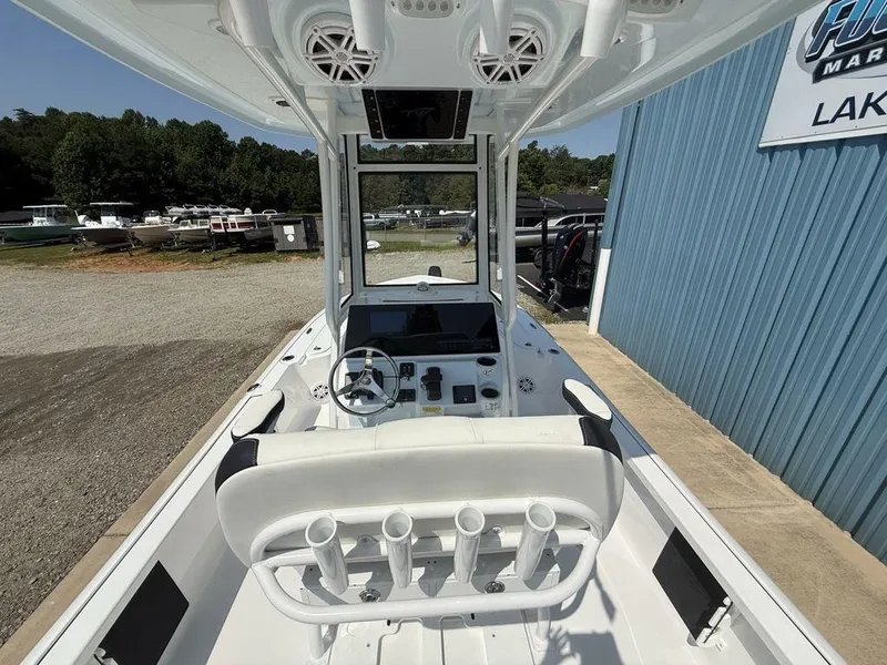 Slide: The Image of 2026 Tidewater 2110 BM boat interior with steering wheel and rod holders, parked near a marina. - 23