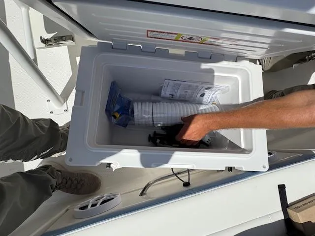 Slide: The Image of Open storage compartment on 2025 Robalo 246 Cayman boat with accessories inside. - 13