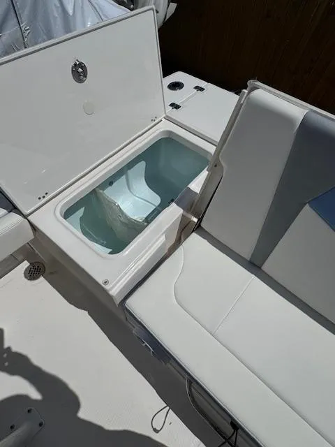 Slide: The Image of 2025 Robalo 246 Cayman boat with open storage compartment and cushioned seating. - 14