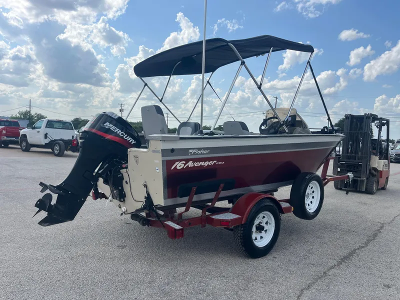 Slide: The Image of 2002 Fisher 16 Pro Avenger boat on trailer, parked outdoors under a cloudy sky. - 16