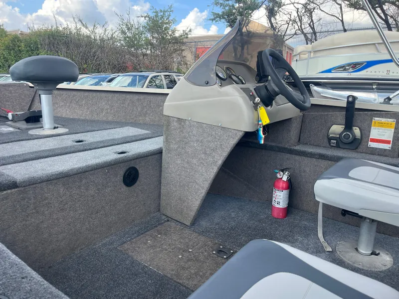 Slide: The Image of 2002 Fisher 16 Pro Avenger boat interior with seating and steering wheel under a blue sky. - 30