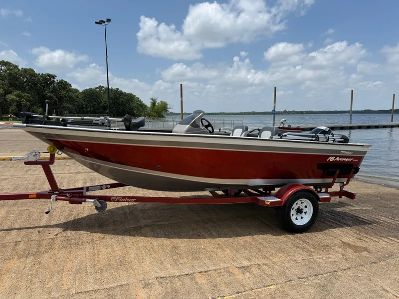Slide: The Image of 2002 Fisher 16 Pro Avenger boat on trailer by the water, under a cloudy sky. - 47