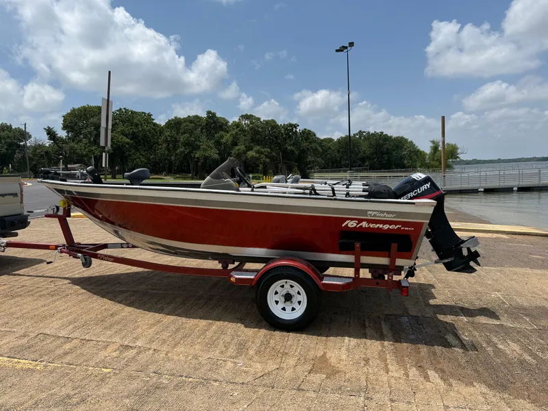 Slide: The Image of 2002 Fisher 16 Pro Avenger boat on trailer by a lake under cloudy sky. - 49