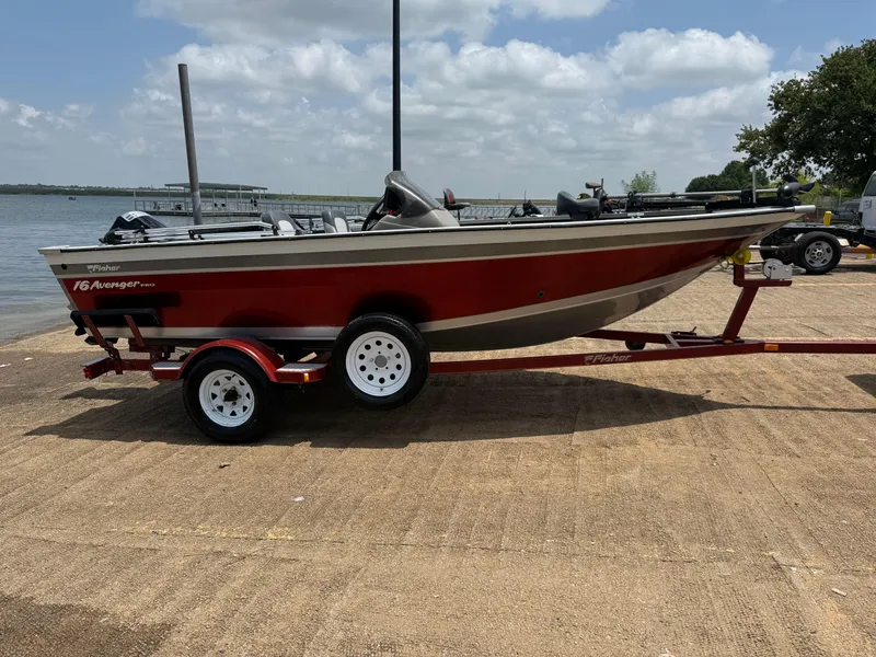 Slide: The Image of 2002 Fisher 16 Pro Avenger boat on trailer by a lake under a cloudy sky. - 50