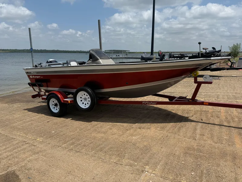 Slide: The Image of 2002 Fisher 16 Pro Avenger boat on trailer by a lake under a cloudy sky. - 51