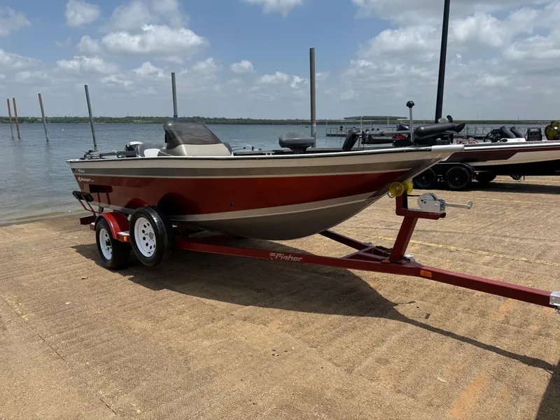 Slide: The Image of 2002 Fisher 16 Pro Avenger boat on trailer by a lake under a cloudy sky. - 52