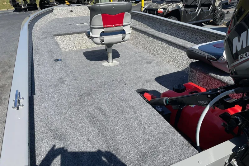 Slide: The Image of 2015 Tracker GV16 LAKER DLX boat interior with seating and motor, parked outdoors. - 7