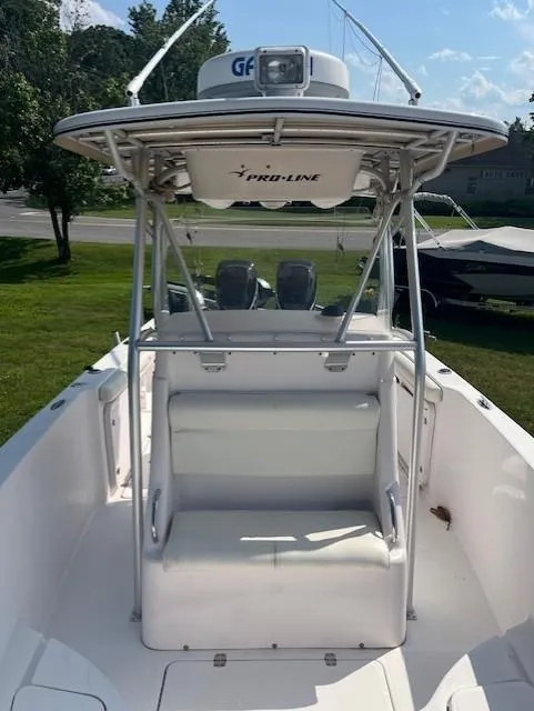 Slide: The Image of 2005 Pro-Line 29 Super Sport boat with T-top and seating, parked on grass. - 3