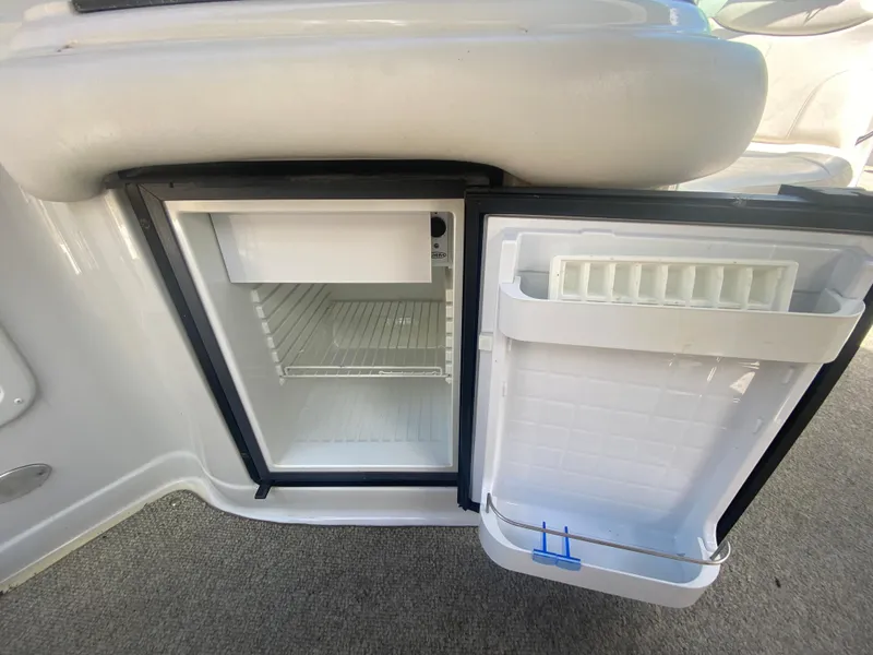 Slide: The Image of Open mini fridge on 2006 Crownline 320 LS boat, showing interior shelves and door storage. - 19