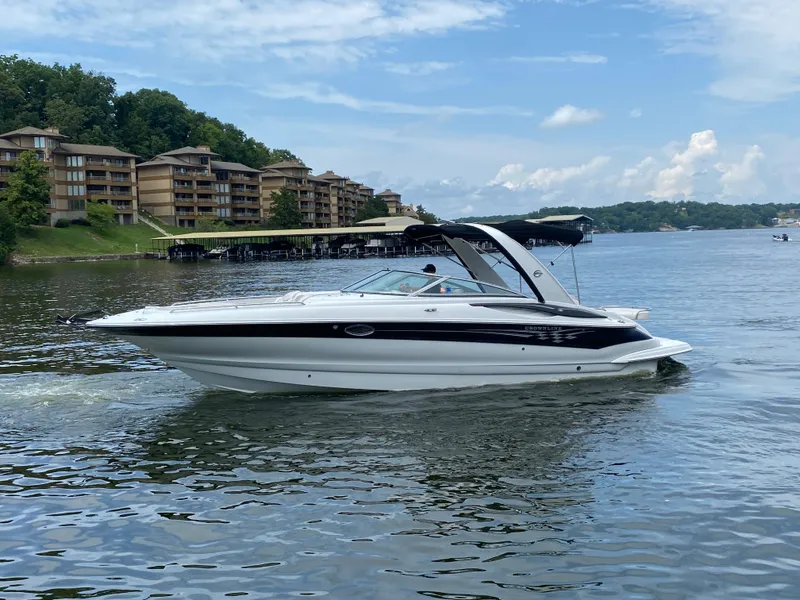 Slide: The Image of 2006 Crownline 320 LS boat cruising on a lake near waterfront buildings. - 2
