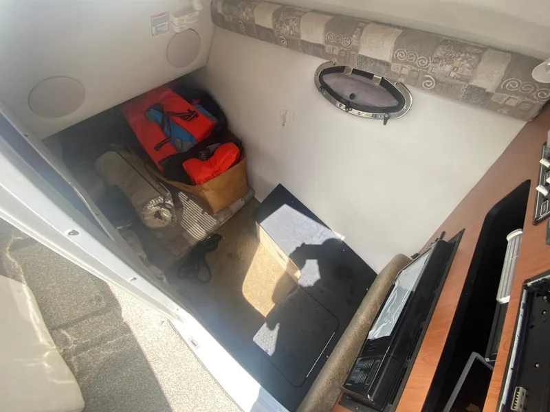 Slide: The Image of 2006 Crownline 320 LS cabin interior with storage and porthole window. - 38