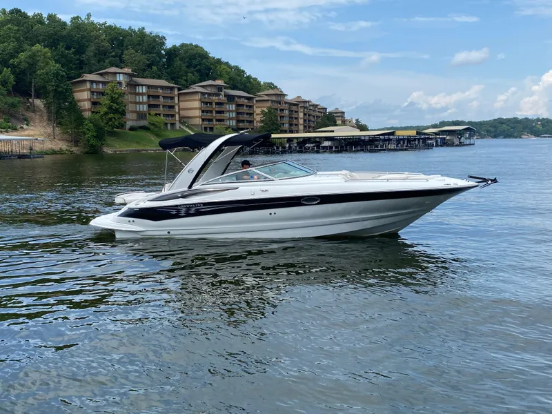 Slide: The Image of 2006 Crownline 320 LS boat cruising on a scenic lake with waterfront buildings. - 4