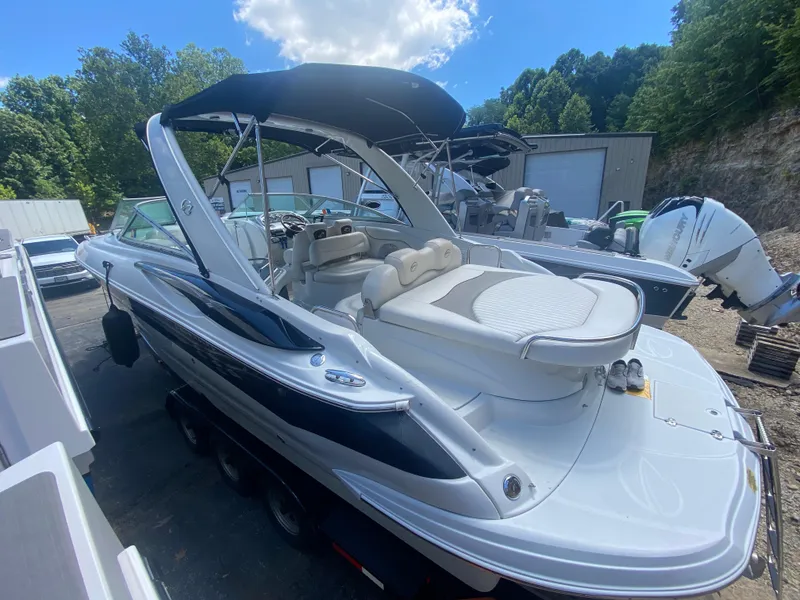 Slide: The Image of 2006 Crownline 320 LS boat with canopy, parked outdoors, surrounded by trees and other boats. - 47