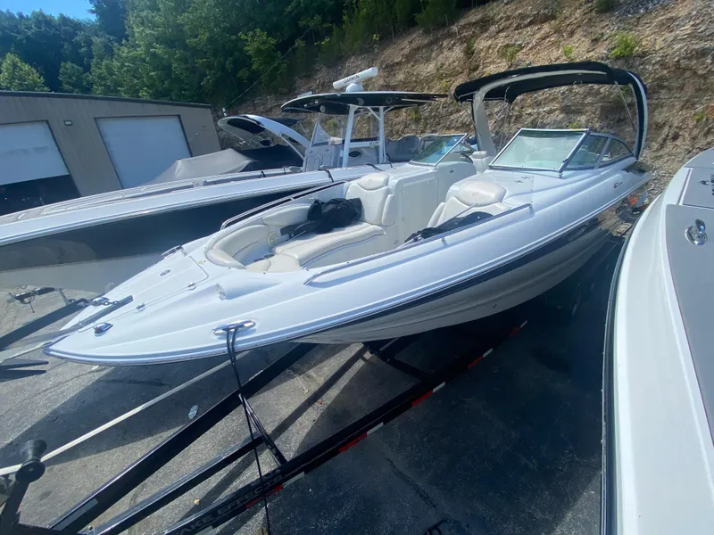 Slide: The Image of 2006 Crownline 320 LS boat on trailer, parked outdoors near trees and buildings. - 48